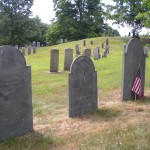 A view a hill from a headstone trio