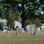 A group of headstones, note the house in back